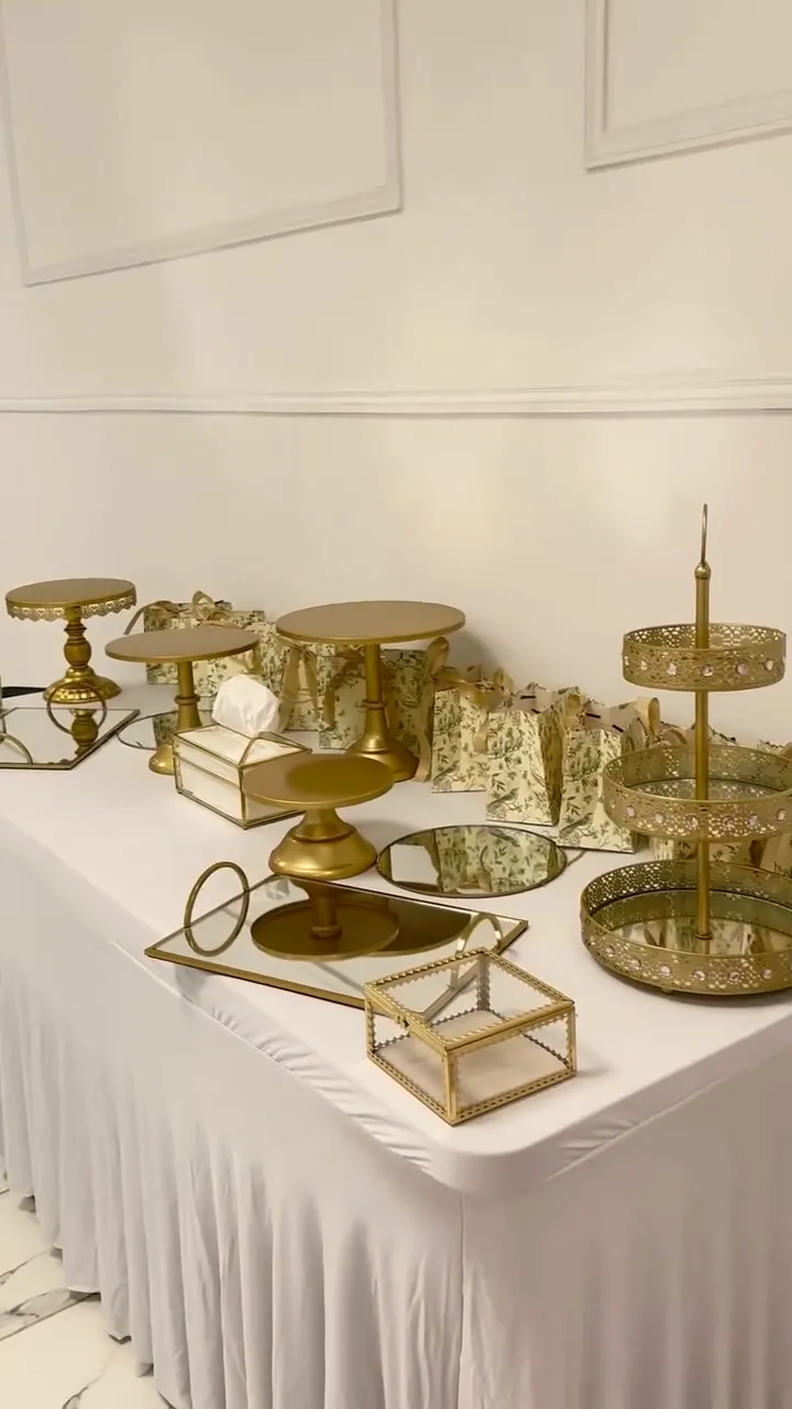 Sweet table blanche garnie de présentoirs dorés, plateaux miroirs et boîtes en verre